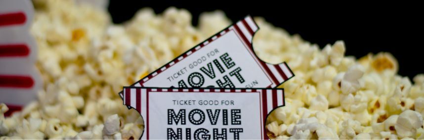 Close up of some popcorn, with two movie night tickets in the popcorn