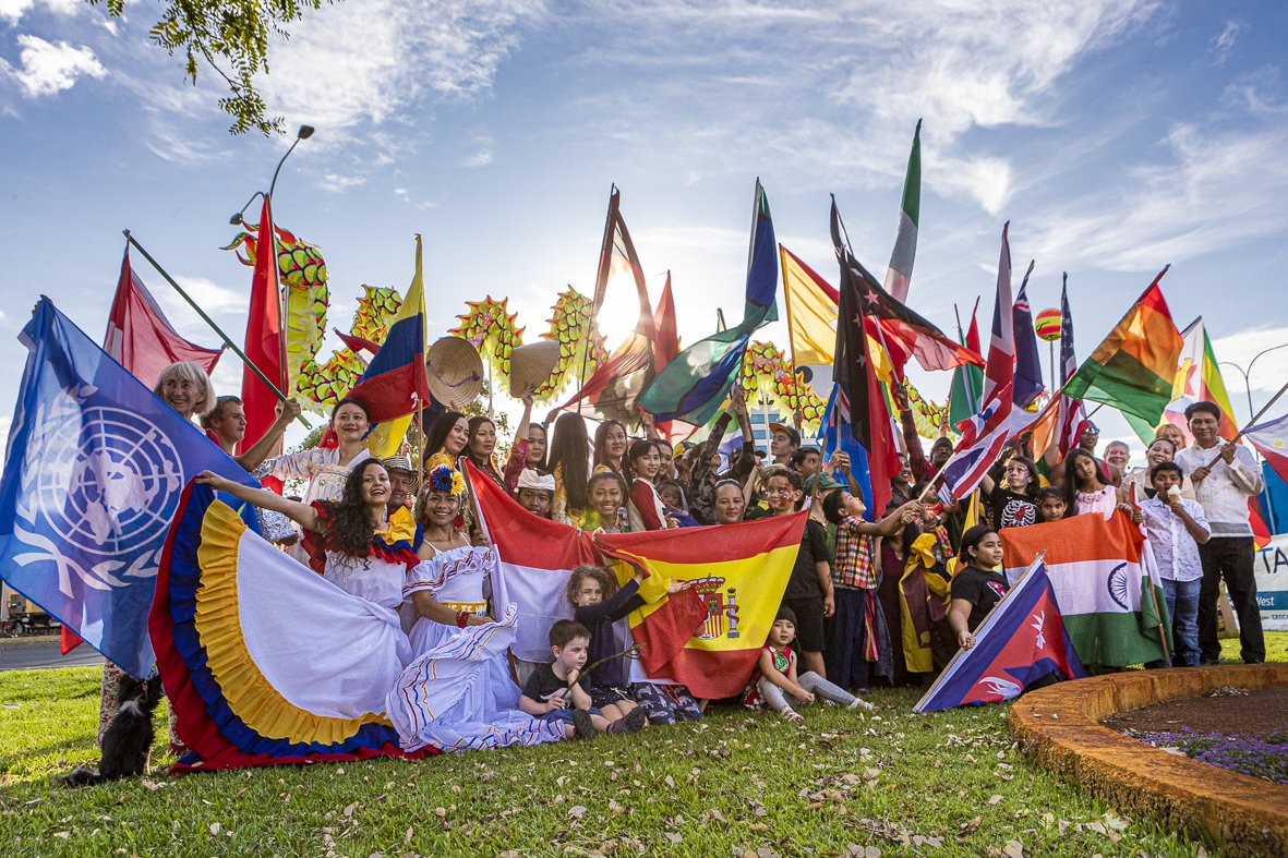 a large group of people in national costumes and holding international flags from many countries